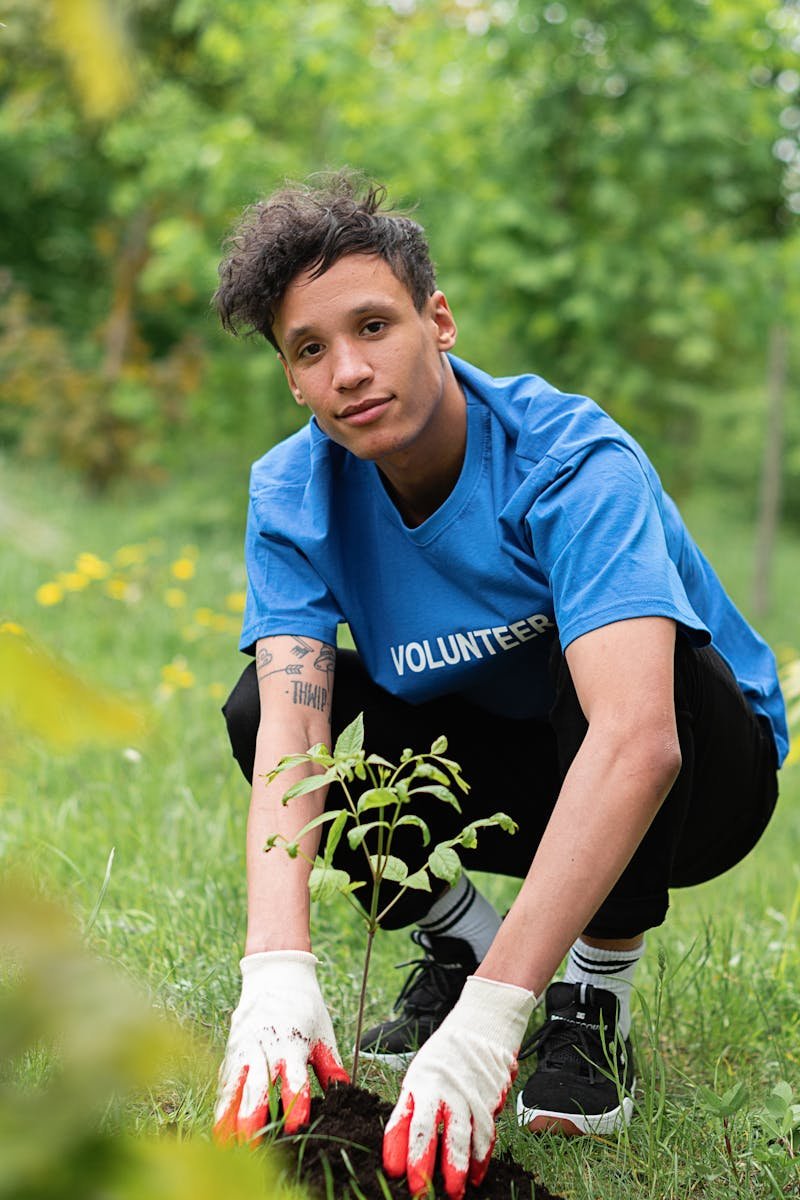 A dedicated volunteer planting a tree sapling in a lush green park environment.